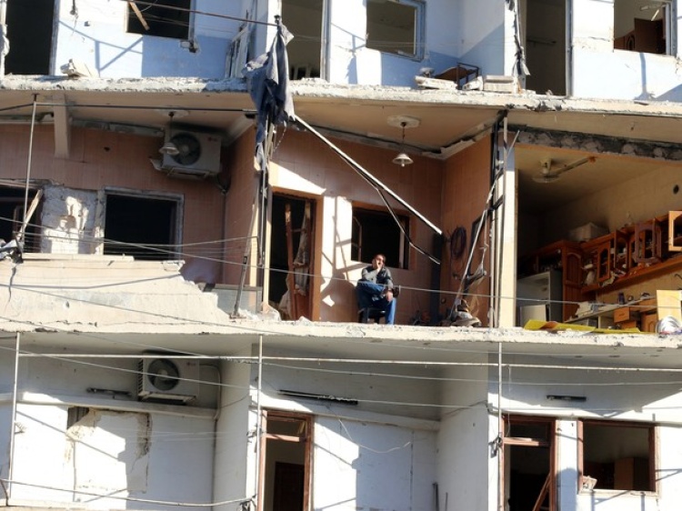 Homem sentado em balcão destruído parcialmente na área rebelde de al-Sukkari, em Aleppo, no norte da Síria, na quarta-feira (19 de outubro) (Foto: Abdalrhman Ismail/ Reuters)