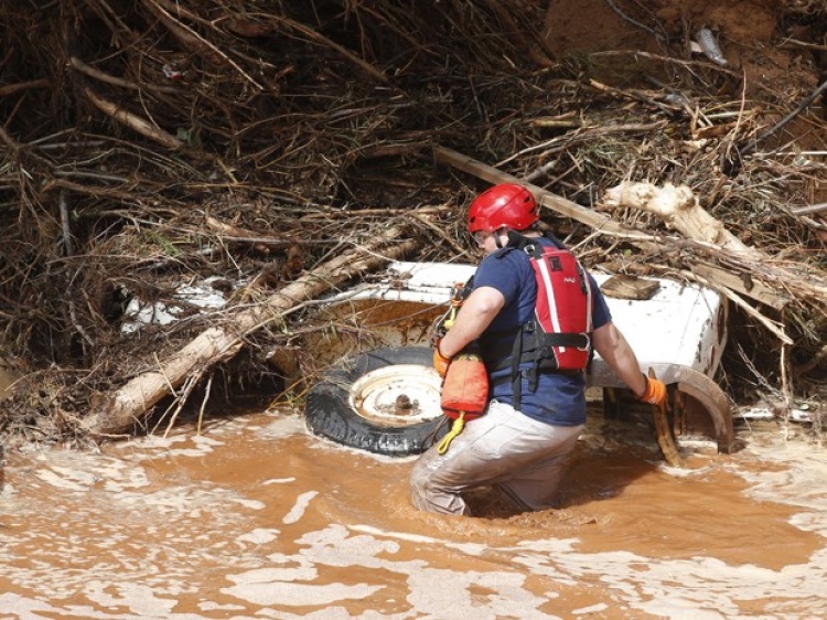 Membro de uma equipe de resgate procura possíveis vítimas em carro enterrado na lama em Short Creek, no local onde duas vans foram arrastadas pelas águas de enchente em Hildale, Utah (Foto: George Frey/Getty Images/AFP)